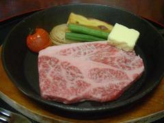 鉄板にミニトマト、インゲンが添えられた能登牛ステーキの写真