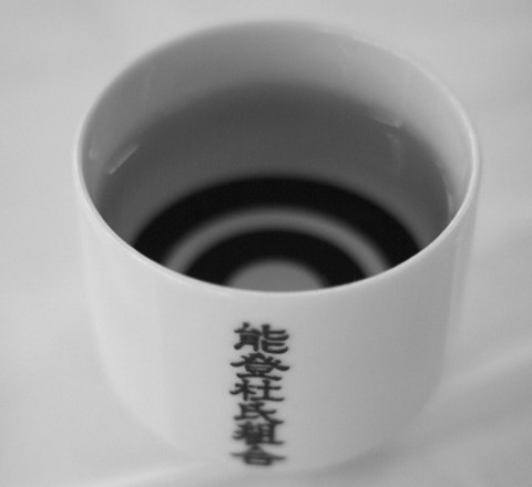 日本酒が注がれた、「能登杜氏組合」の文字が入っている器の写真