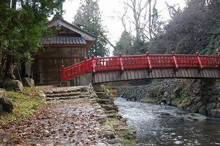 祠の前に赤色の手すりの橋がある写真