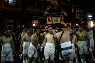 上半身が裸姿の男性たちが神輿を担いでいる写真