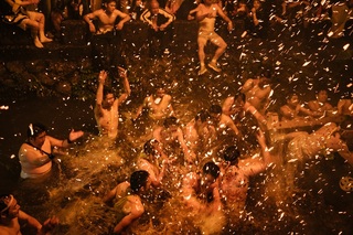 上半身が裸姿の男性たちが水の中に飛び込んでいる写真