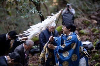 装束を着た神主が頭を下げている参拝者の方々に祓串を振っている写真
