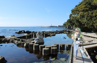 海沿いの遊歩道を歩いている女の子のイラストと実際の九十九湾遊歩道の写真を合成した画像