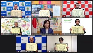 パソコンの画面に野田聖子衆議院議員を中心にして7人の男性が賞状を広げて映っている写真