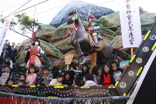 鎧兜姿の武将が馬に乗った飾りがある山車に乗っている子供たちの写真