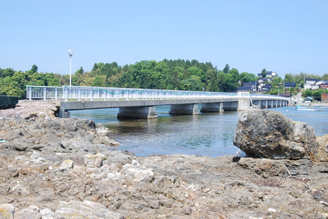ごつごつとした岩場が広がり、赤崎海岸と平島をつなぐ釣り桟橋の写真