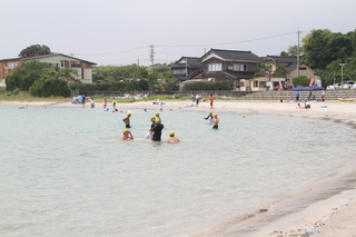 浅瀬のところで海水浴を楽しんでいる人たちの写真