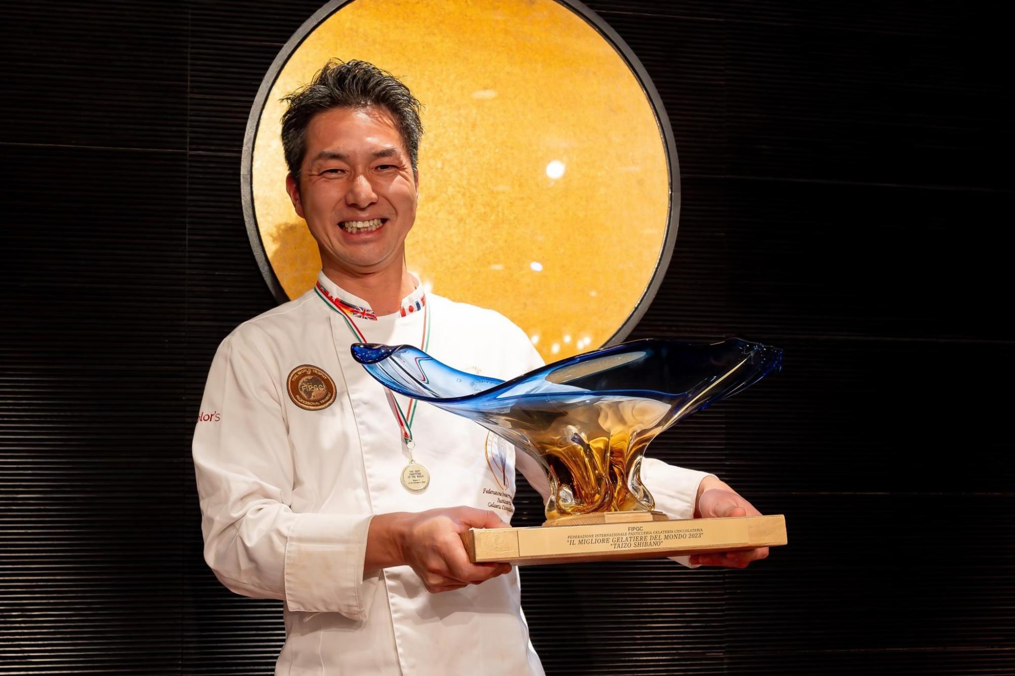 トロフィーを受け取り横を向いた柴野大造さんの写真