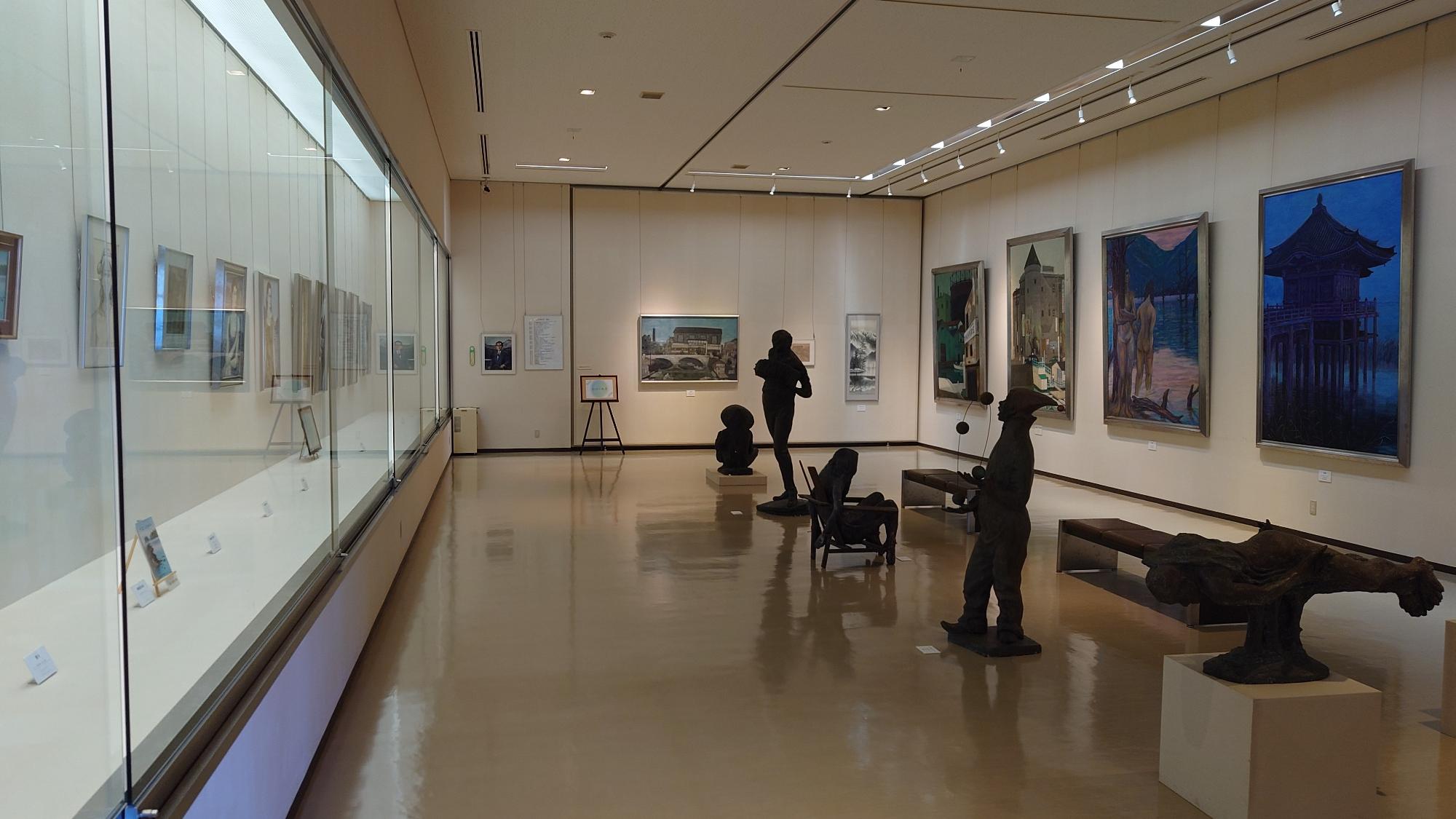 額に入った作品がガラスケースに展示されている1階展示室の写真