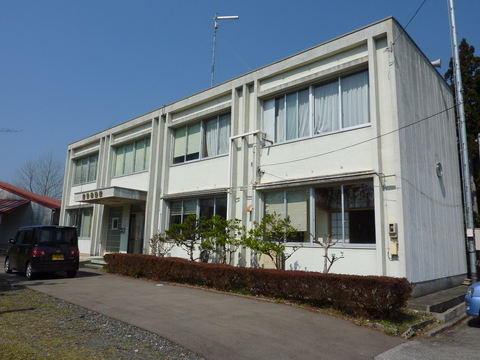 白い外壁で2階建て、大きな窓がありそばに手入れされた植栽がある建物の外観写真