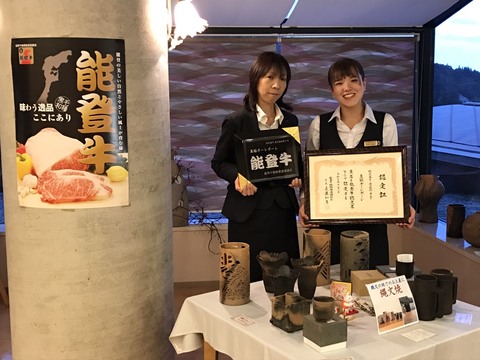 関係者の女性2人がそれぞれ「能登牛」と書かれたプレートと額に入った認定書を持ち記念撮影を行っている写真